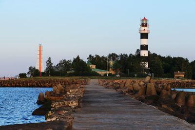 Lighthouse amidst buildings against clear sky