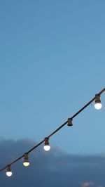 Low angle view of lighting equipment against clear blue sky