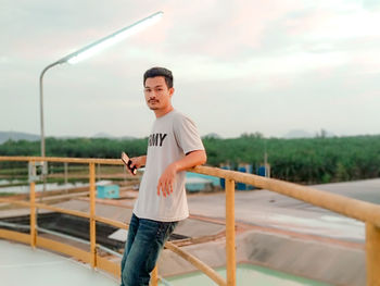 Full length of young man standing on railing