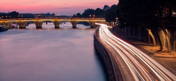 High angle view of light trails on road by river during sunset in city