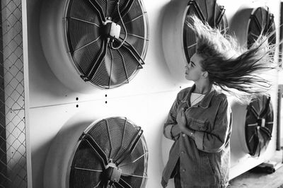 Teenage girl standing against exhaust fans