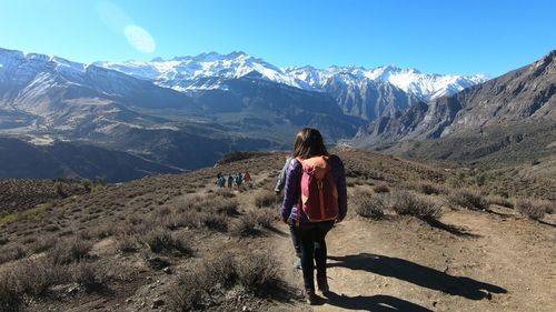 Rear view of woman standing on snowcapped mountain