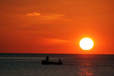 Silhouette people in boat at sea against sky during sunset