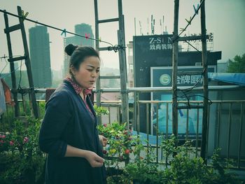 Young woman standing against plants