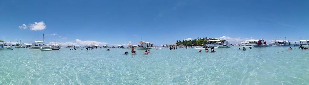 Group of people on beach against blue sky