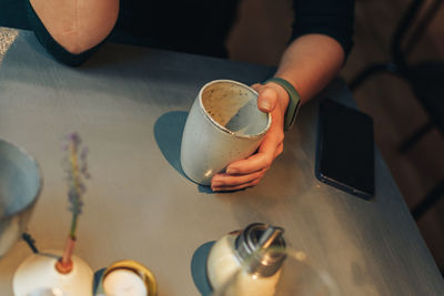 High angle view of woman holding coffee cup on table