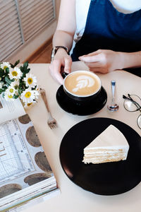 High angle view of woman holding coffee cup on table