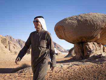 Man standing on rock in desert against clear sky