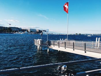 Swiss flag on pier in sea against sky