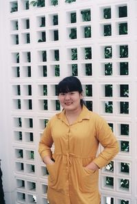 Portrait of smiling young woman standing against built structure