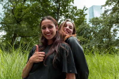 Portrait of cheerful friends standing on field