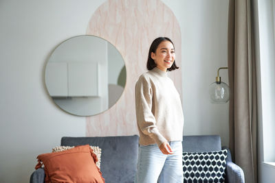 Portrait of young woman standing against wall