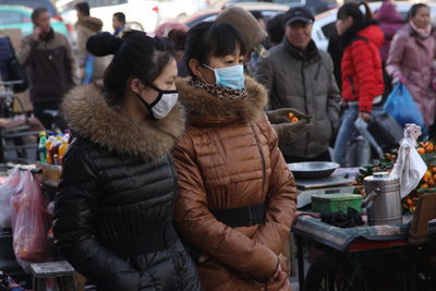 Female friends wearing mask while standing in market