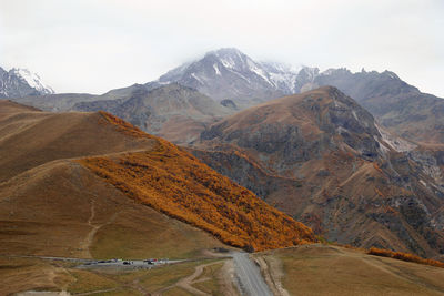 Road in the mountains in autumn time on a background of caucasus mountains with snowy peak, georgia.