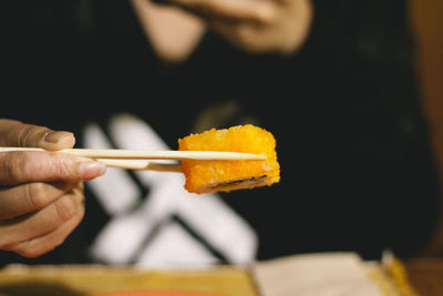 Midsection of person having sushi with chopsticks
