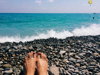 Low section of person at beach against sky