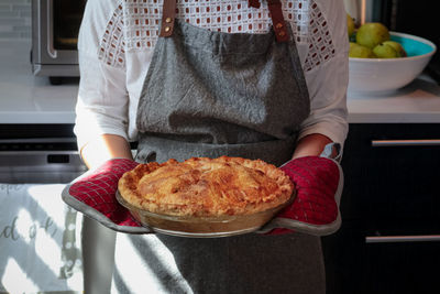 Midsection of woman holding apple pie at home 