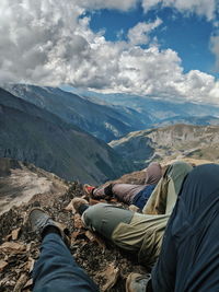 Low section of people on mountain against sky