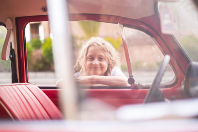 Portrait of smiling girl leaning on car door