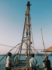 Rear view of people on sailboat against clear sky