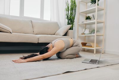 Low section of woman sitting on sofa at home