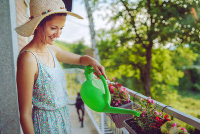 Midsection of woman wearing hat standing against plants