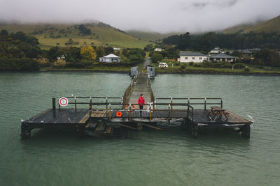 Woman on a red jacket standing at port levy jetty, banks peninsula, nz