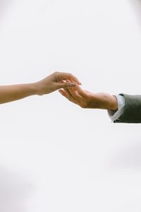 Low angle view of couple hand to hand against white background