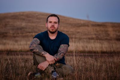 Portrait of young man sitting on land