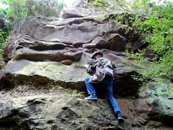 Rear view of men sitting on rock