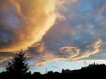 Low angle view of silhouette trees against dramatic sky