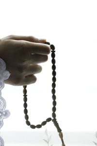 Close-up of hand holding cross against white background