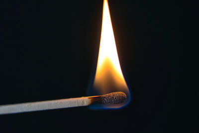 Close-up of lit candle against black background