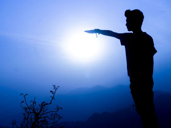 Rear view of silhouette man standing against sky