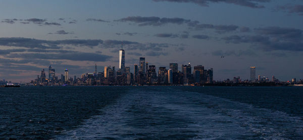 Lower manhattan skyline at sunset viewed from the water.