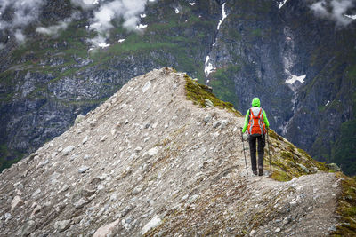 Full length rear view of woman hiking on mountain peak