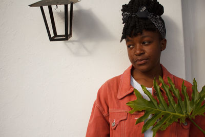 Side view of young woman standing against wall