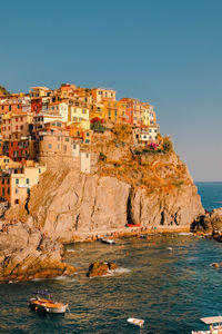 Buildings by sea against clear blue sky