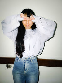 Young woman standing against wall