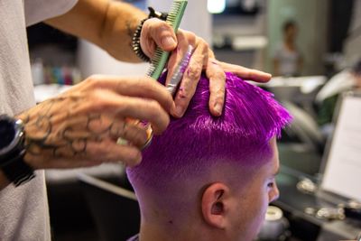 Midsection of hairdresser cutting customer hair