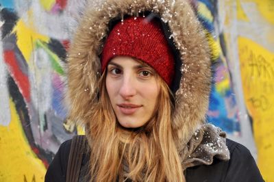 Portrait of smiling young woman standing in city during winter