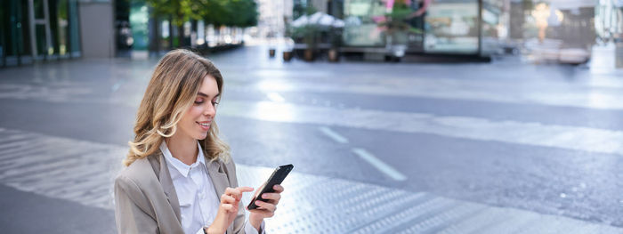 Portrait of young woman standing in city