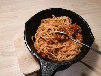 High angle view of pasta served in bowl with spoon on wooden table 