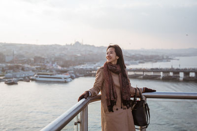 Portrait of young woman standing against river