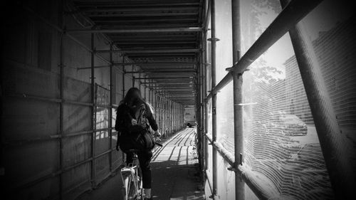 Rear view of woman riding bicycle in building passage