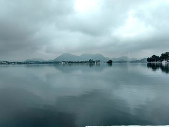 Scenic view of lake and mountains against cloudy sky