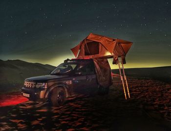 Vintage car on illuminated land against sky at night