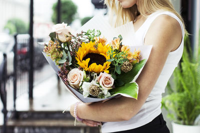 Midsection of woman holding flowers