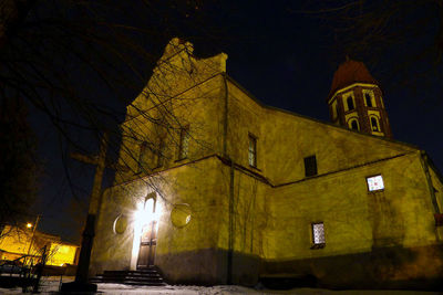 Low angle view of illuminated street light against building at night