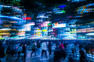 People walking on illuminated street at night